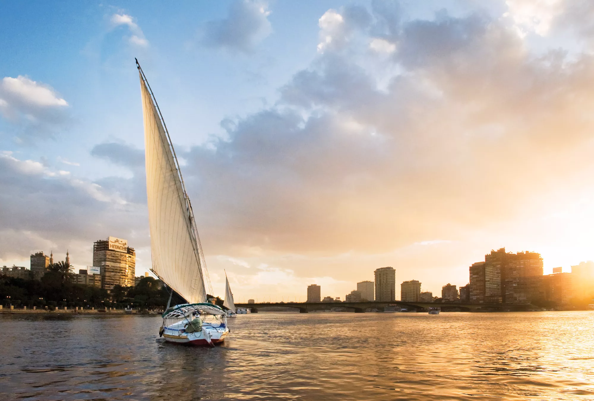 A felucca sails past Fairmont Nile City at sunset